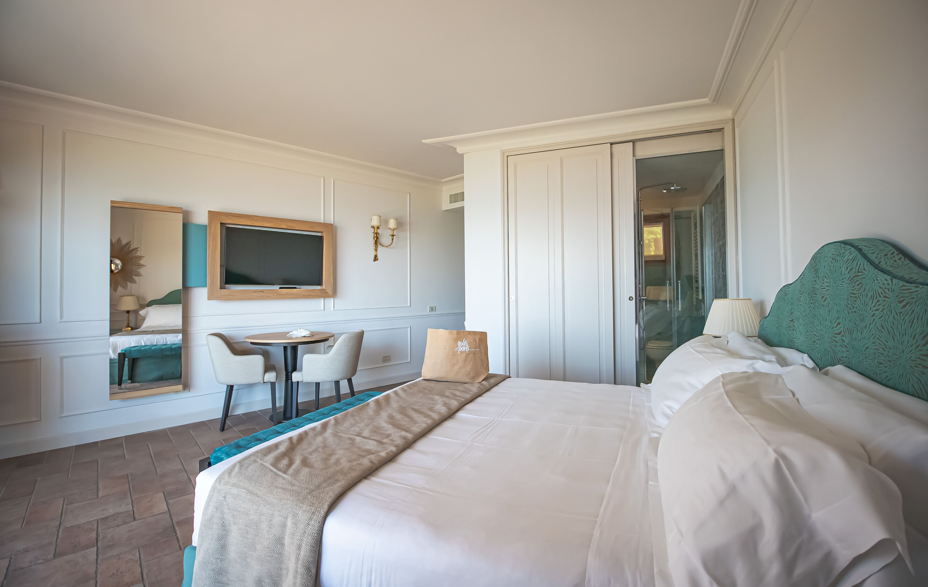 Una camera d'albergo con un letto grande, una scrivania con una sedia, una TV e un armadio.