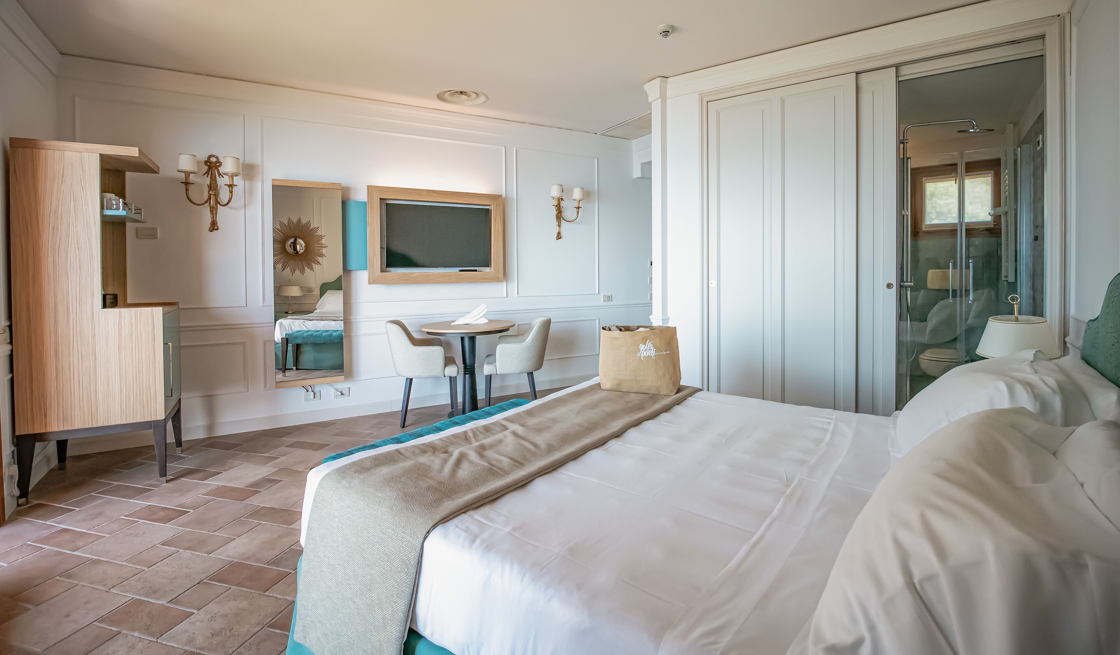Een hotelkamer met een bed, een bureau, een stoel, een kleine tafel, een spiegel en een kledingkast.