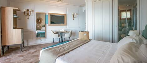 Een hotelkamer met een bed, een bureau, een stoel, een kleine tafel, een spiegel en een kledingkast.