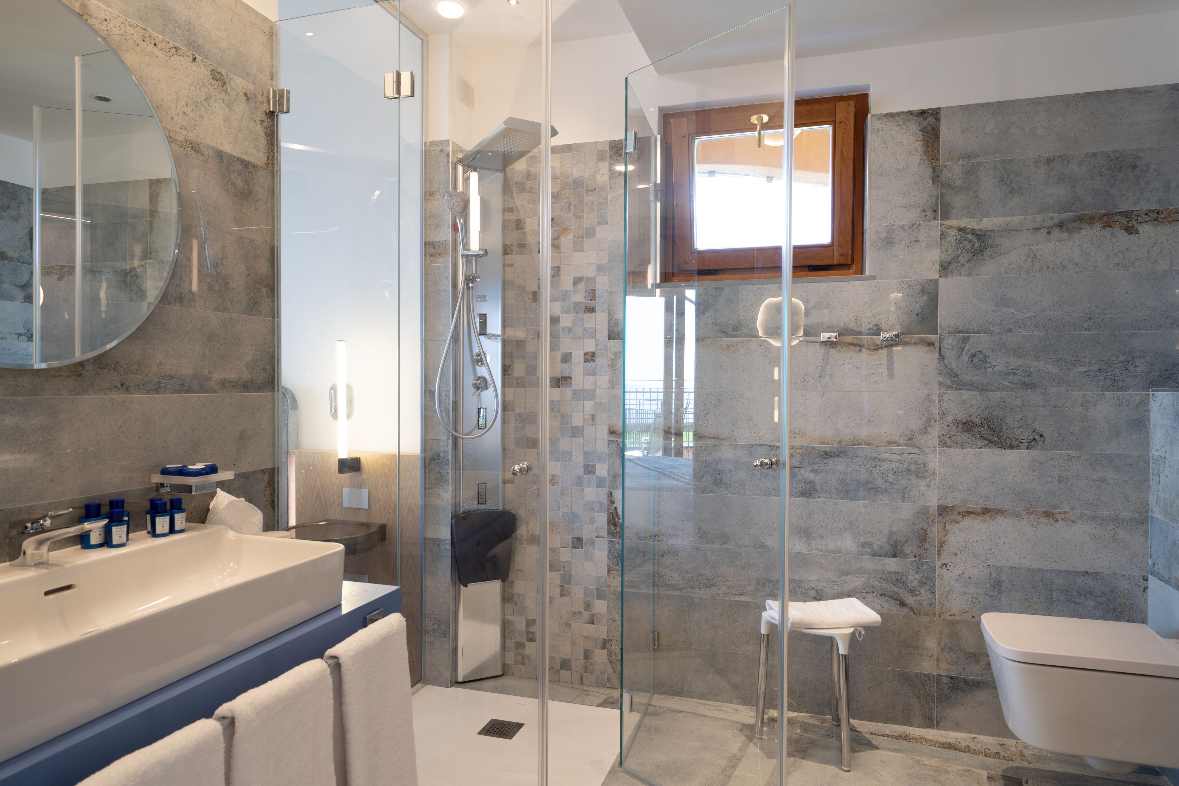 Ein modernes Badezimmer mit einer gläsernen Duschkabine, einem großzügigen Waschbecken mit Spiegel und einer Toilette.