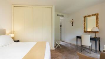 Habitación de hotel con cama, escritorio, silla, espejo y lámpara.