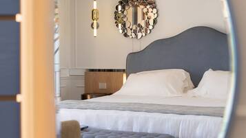 A bedroom with a large bed, a bedside table, a mirror, and a hanging light fixture.