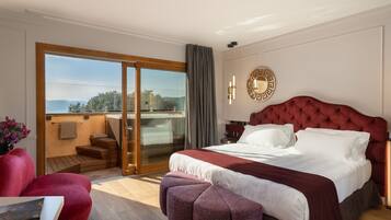 Una habitación de hotel moderna con una cama grande, un sillón tapizado en rojo, una mesita y vistas al exterior a través de una puerta corrediza de vidrio.