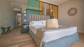 A modern hotel room with a large bed, a bedside table, a phone, and a mirror.