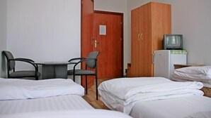 Una habitación de hotel con dos camas, un armario de madera, una mesita con sillas y un televisor.