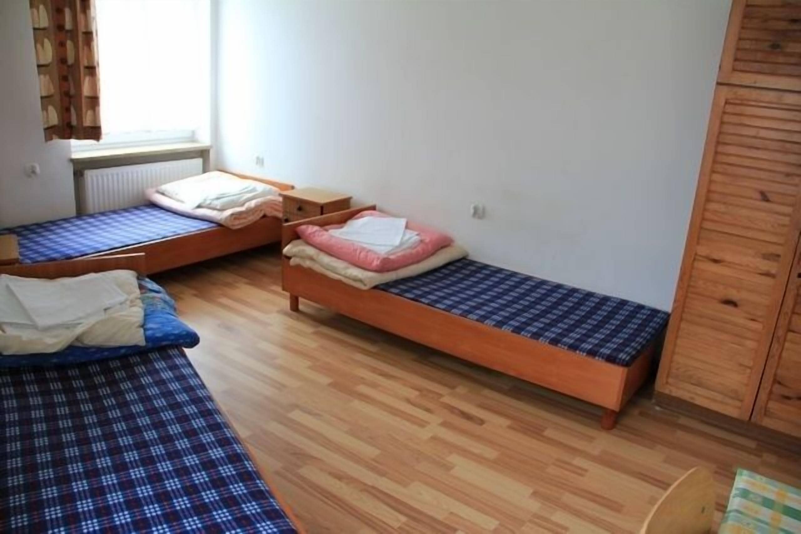 A small, tidy room with two single beds, a wooden wardrobe, and a radiator.