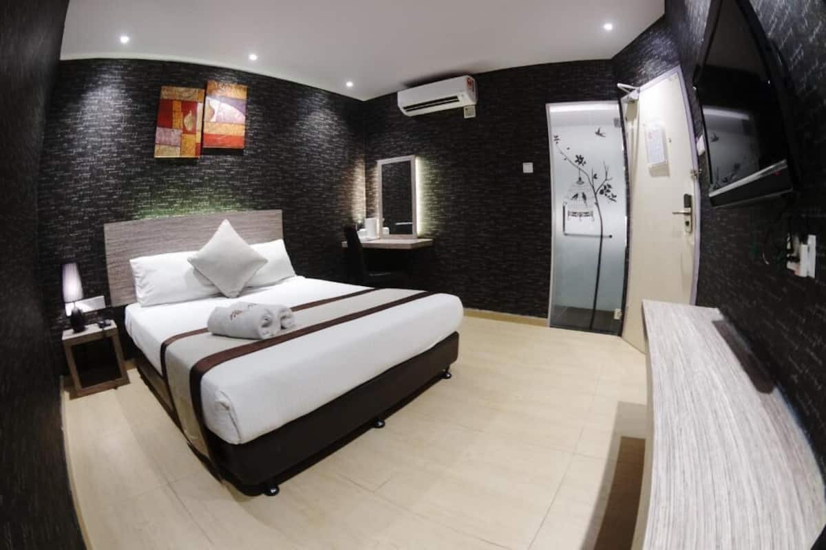 A modern hotel room with a large bed, bedside table, mirror, and a TV.