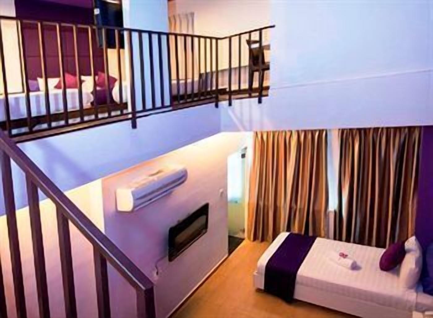 Une chambre d’hôtel avec un lit superposé, un petit bureau, une fenêtre avec des rideaux et un escalier.