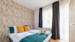 A hotel room with a bed, a nightstand, a window with curtains, and a patterned wall. - Prince Apartments (Budapest)