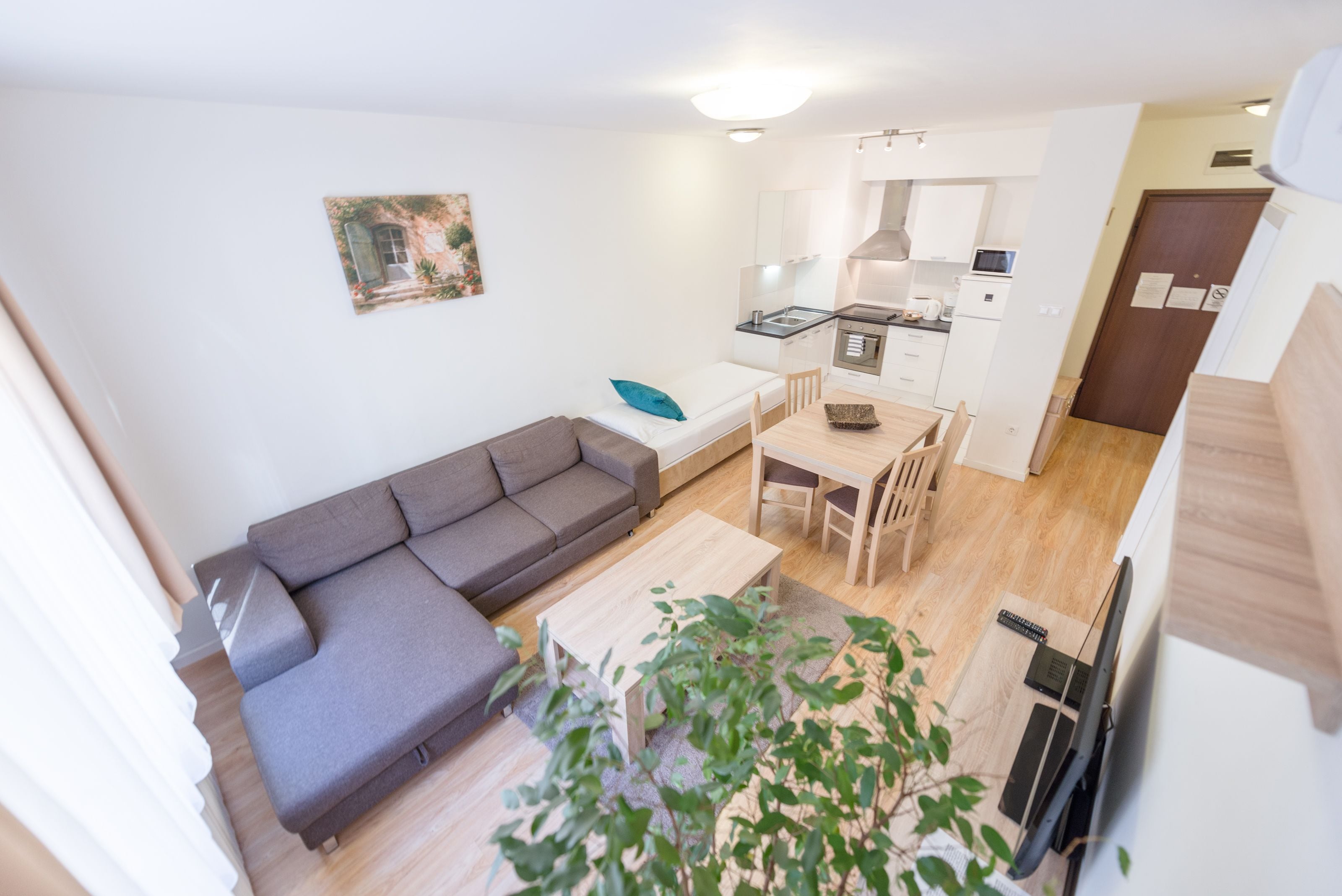Un espace de vie compact comprenant un canapé, une table à manger, une petite cuisine et un téléviseur.
