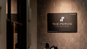 A sign for 'The Period' hotel with a modern design, mounted on a tiled wall. - The Period Pratunam (Bangkok)