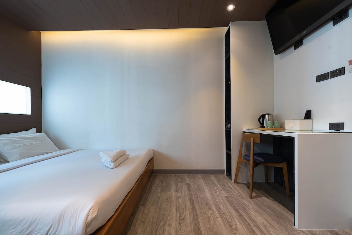 A modern hotel room with a bed, a desk, and a television.