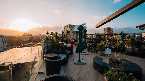 A rooftop terrace with outdoor seating, potted plants, and a view of the city skyline during sunset. - Monarch Hotel (Addis Ababa)