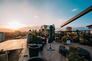 A rooftop terrace with outdoor seating, potted plants, and a view of the city skyline during sunset. - Monarch Hotel (Addis Ababa)