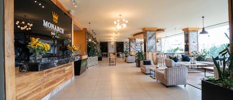 A spacious lobby with a reception desk, seating area, and large windows.