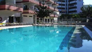 Una piscina al aire libre, sombrillas, tumbonas