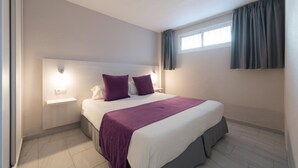 A bedroom with a bed, two bedside tables, a window with curtains, and a wall-mounted light fixture. - Las Gacelas (San Bartolomé de Tirajana)