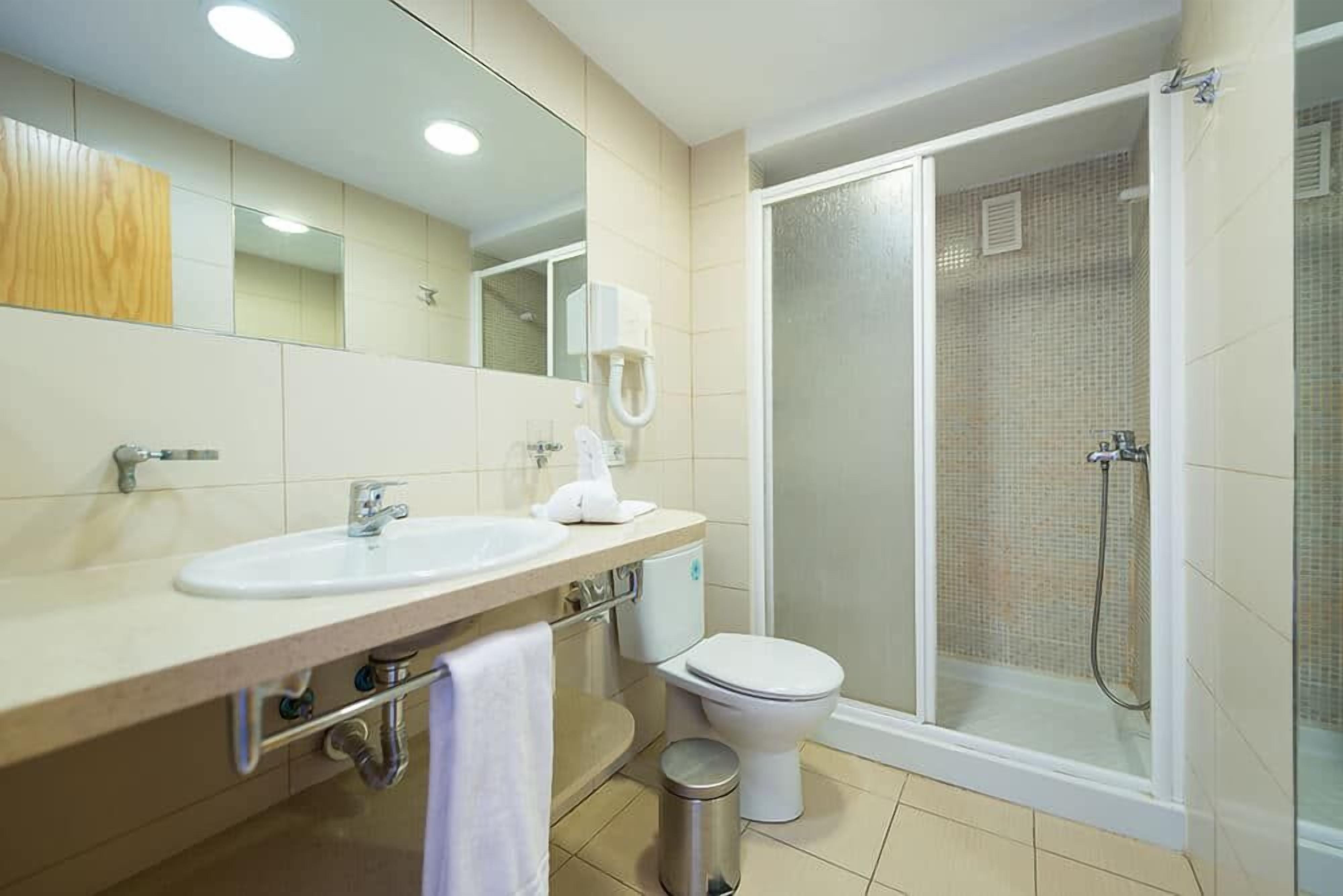 Baño con lavabo, inodoro y zona de ducha.