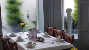 Un comedor con mesas dispuestas para el desayuno, incluyendo platos, tazas y cubiertos.