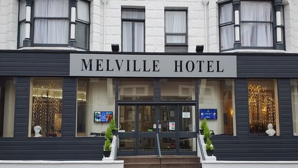 El exterior del Hotel Melville, con una fachada clásica, ventanas amplias y una entrada destacada.