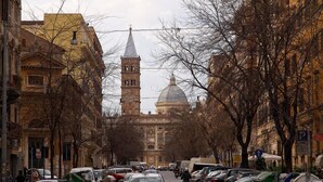 A cobblestone street lined with parked cars and buildings, including a prominent tower with a dome. - Belhorizon Guest House (Rome)