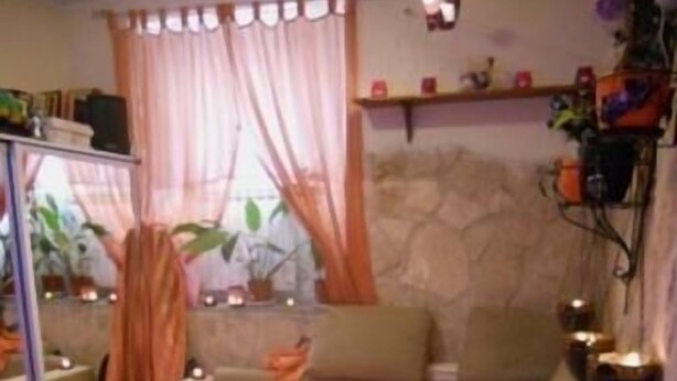 A bedroom with a bed, a sofa, a mirror, a small table with a candle, and a wall-mounted shelf with decorative items. - Belhorizon Guest House (Rome)