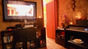 A living room with a television, a piano, and a bookshelf. - Belhorizon Guest House (Rome)