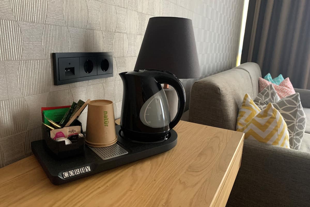 Ein Hotelzimmer mit einer Kaffeemaschine auf einem Tablett, einer Lampe und einer Steckdose.