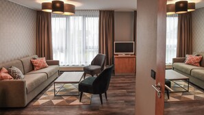 A modern hotel room with a sofa, armchair, and a flat-screen TV. - EuroStar Hotel (Castrop-Rauxel)