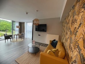 A modern living room with a sofa, a coffee table, and a TV mounted on the wall. - EuroStar Hotel (Castrop-Rauxel)