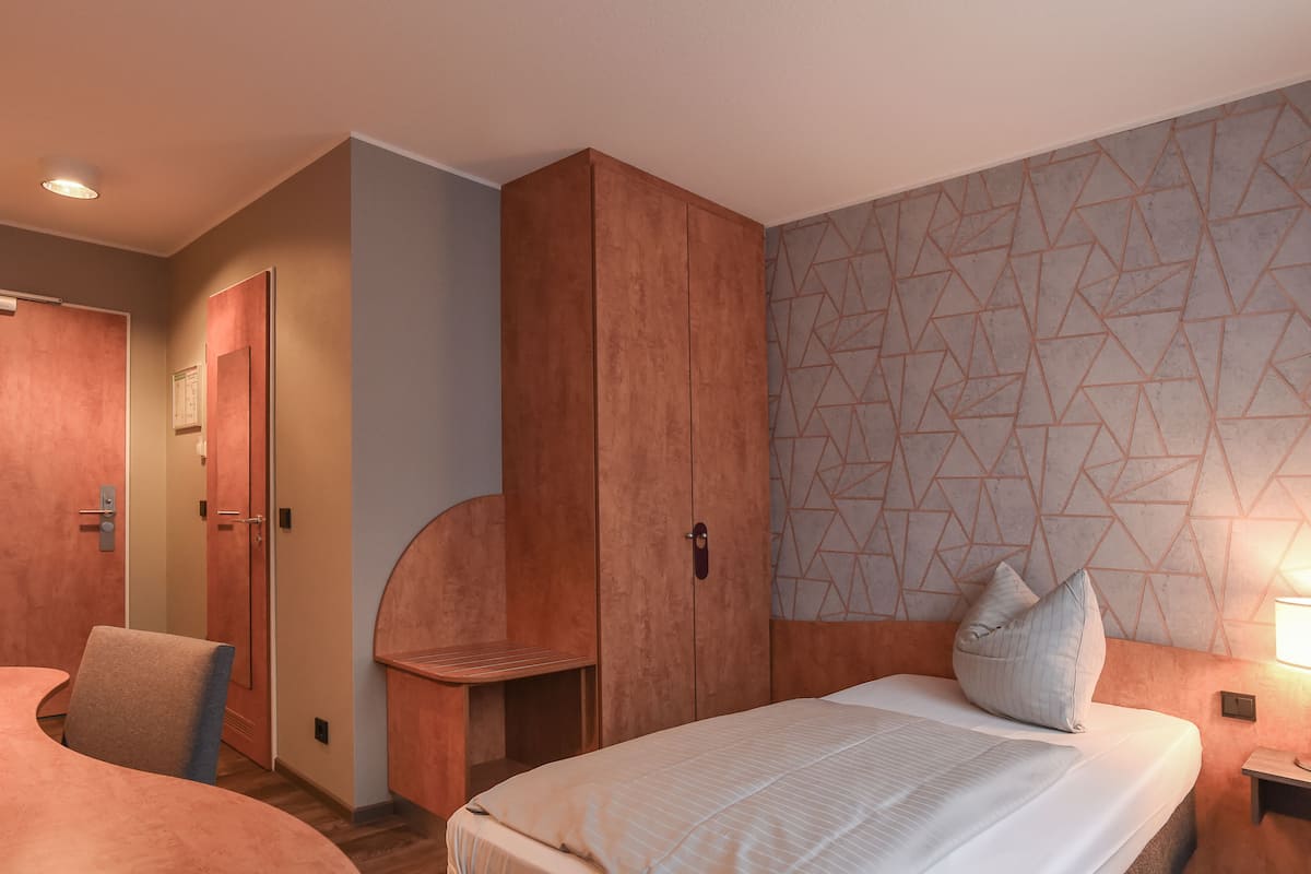 Ein Hotelzimmer mit einem Bett, einem Schreibtisch, einem Kleiderschrank und einer Wand mit geometrischem Muster.