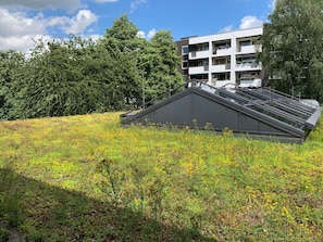 A modern building with a flat roof and a sloped section, surrounded by greenery and trees. - EuroStar Hotel (Castrop-Rauxel)