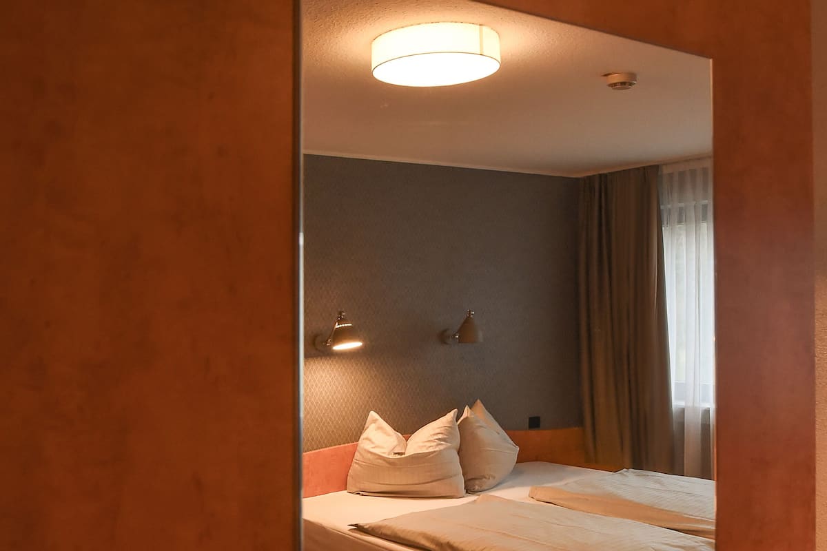 Ein Hotelzimmer mit Bett, Sessel, Nachttisch und Lampe.