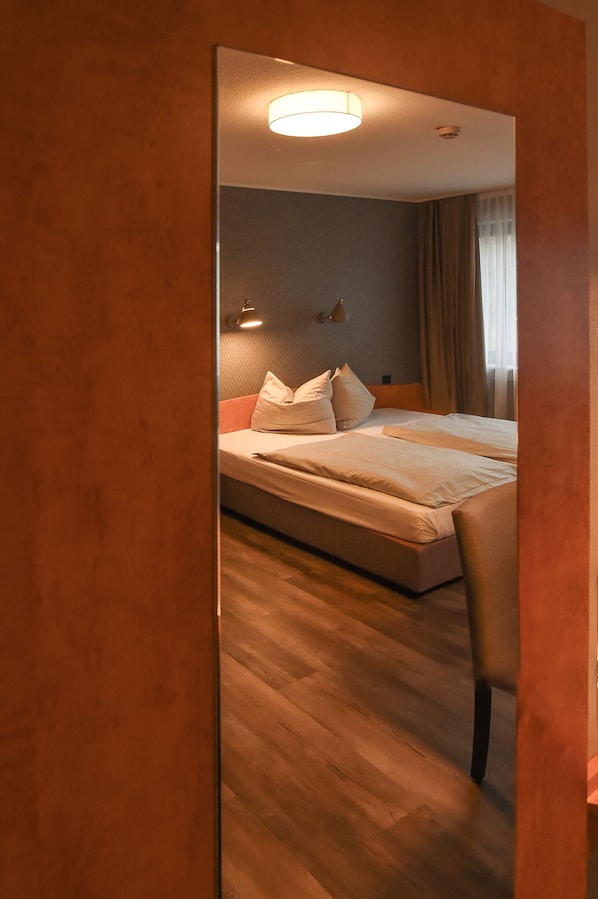 A hotel room with a bed, a chair, a nightstand, and a lamp. - EuroStar Hotel (Castrop-Rauxel)