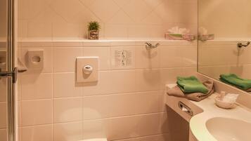 Ein Badezimmer mit Toilette, Waschbecken, Spiegel und einer kleinen Pflanze an der Wand.