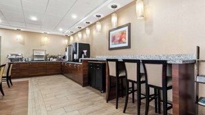 Una cucina moderna con piani di lavoro in granito, sgabelli da bar e una macchina da caffè.