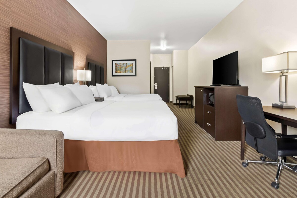 Una habitación de hotel con una cama grande, un escritorio, un televisor y una silla.