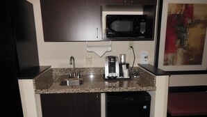 Une petite cuisine équipée d’un four à micro-ondes encastré, d’une machine à café et d’un évier.