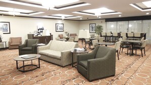 Un hall d’hôtel avec des canapés, des fauteuils, une table basse et un espace repas comprenant des tables et des chaises.