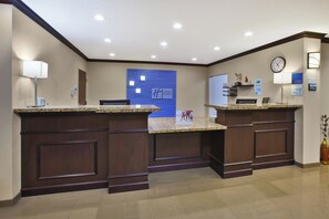 A hotel reception area with a marble counter, a clock, and a sign indicating check-in and check-out times. - Holiday Inn Express & Suites Washington - Meadow Lands by IHG (Canonsburg)