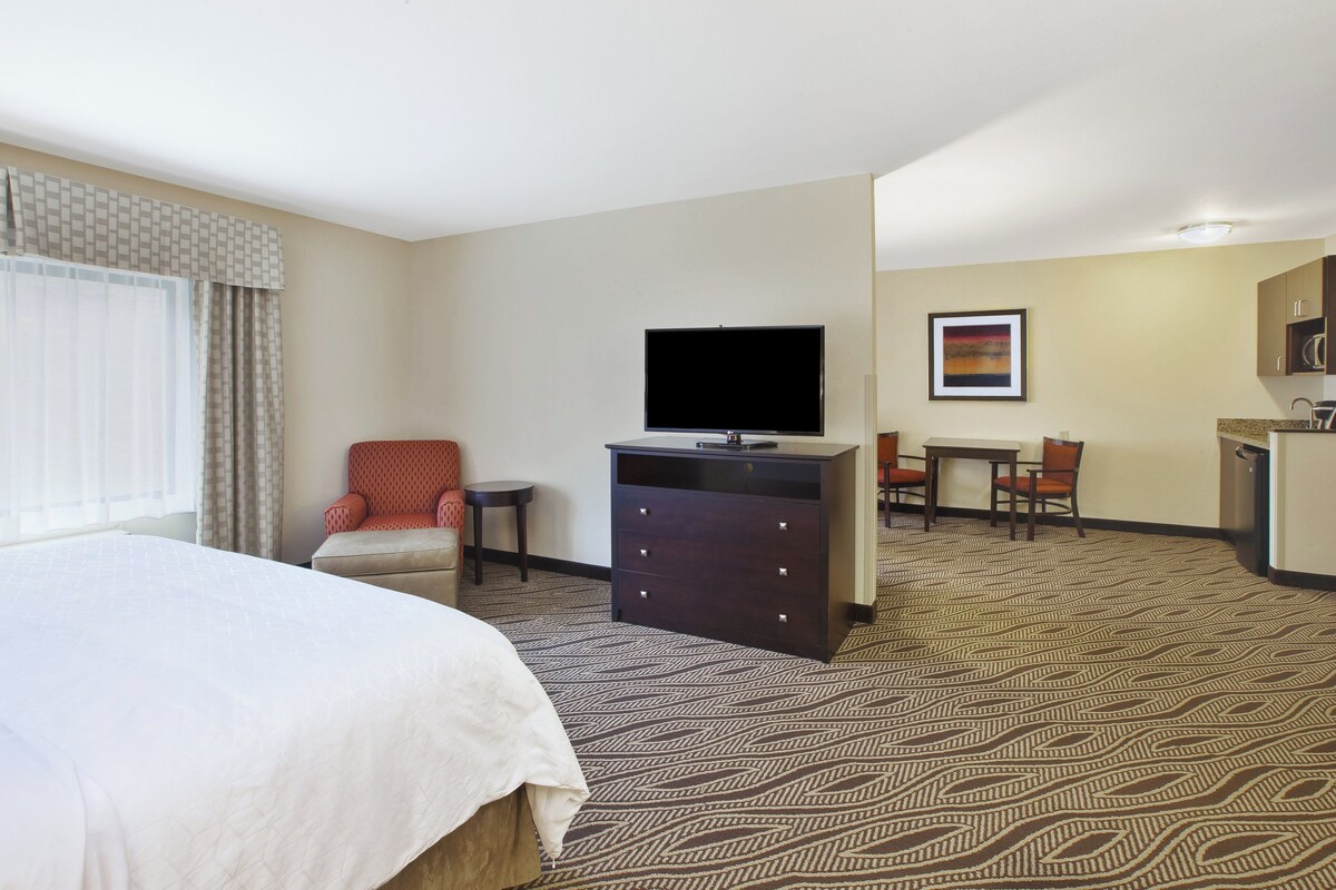 Een hotelkamer met een bed, een bureau, een stoel, een televisie en een kleine tafel.