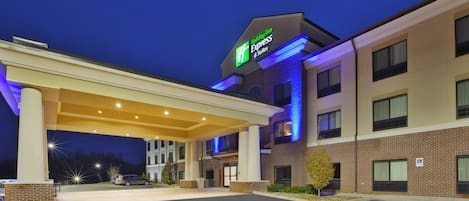 A Holiday Inn Express & Suites with a covered entrance, parking lot, and a brick facade.