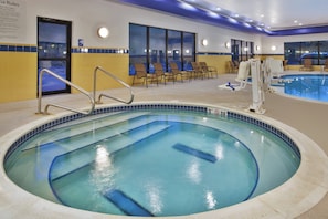 Una piscina con borde de azulejos, un puesto de socorrista y una zona de estar con sillas.
