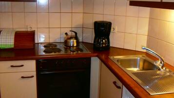 A compact kitchen with white cabinets, a black stove, a coffee maker, and a dishwasher.