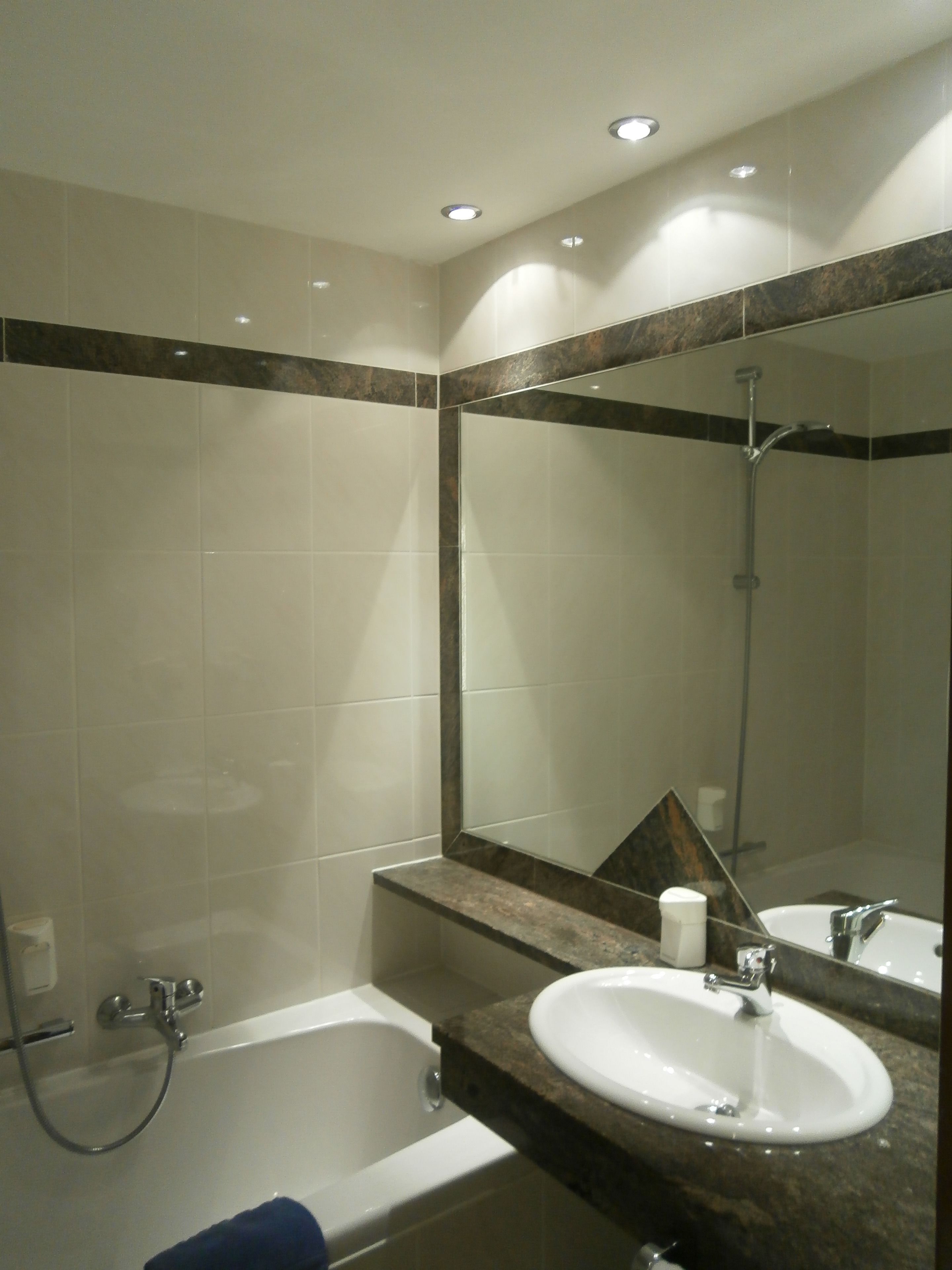 A bathroom with a bathtub, a sink, and a large mirror.