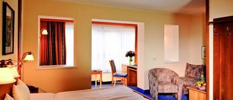 A hotel room with a bed, a desk, a chair, and a sofa.