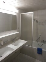 Un baño con dos lavamanos, un espejo, una ducha y un perchero para toallas.