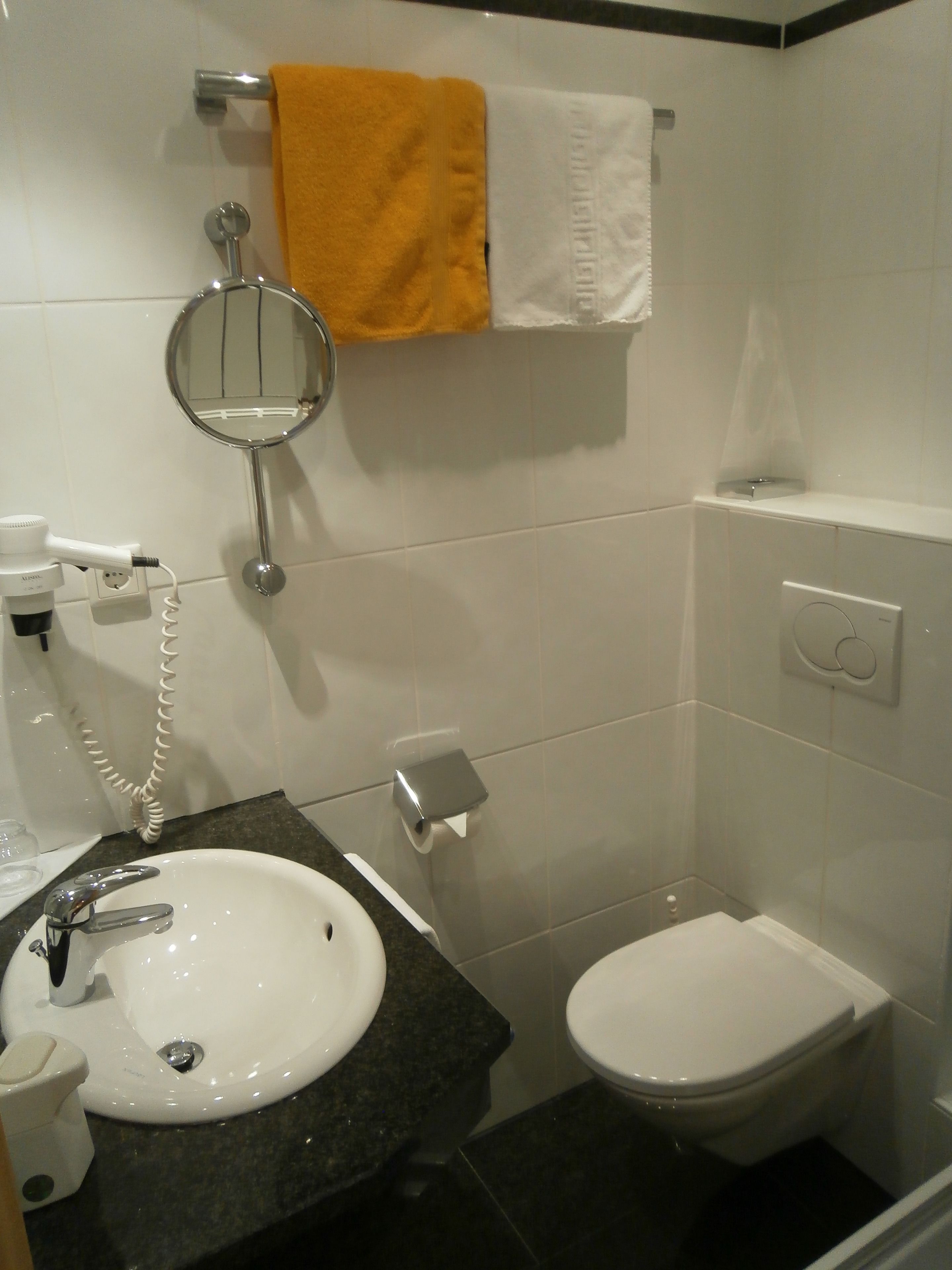 A bathroom with a sink, toilet, and a towel rack with two towels.