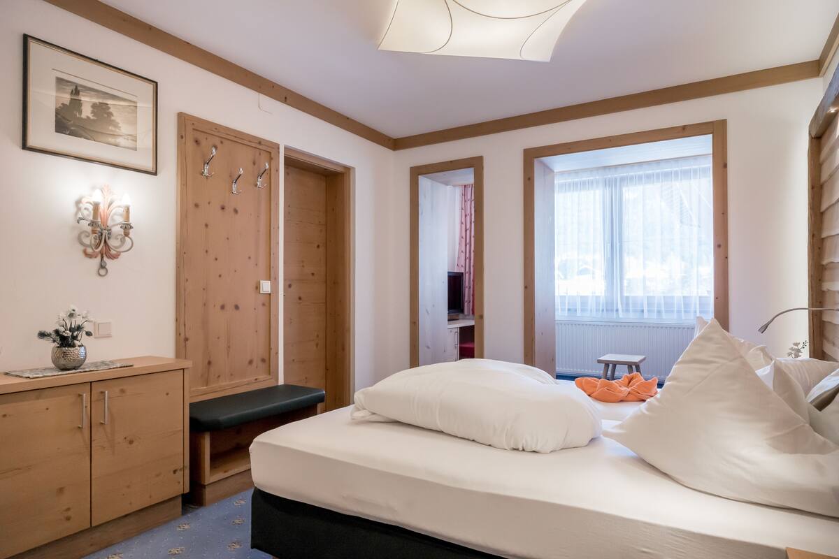 Une chambre à coucher avec un lit, une armoire en bois et un banc.