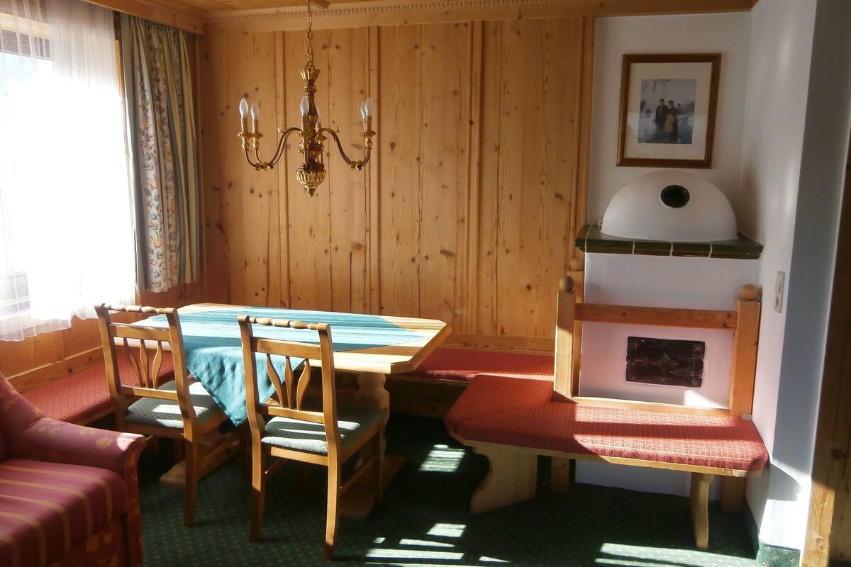 Une pièce aux murs lambrés, comprenant une table à manger, des chaises, un banc et une cheminée.